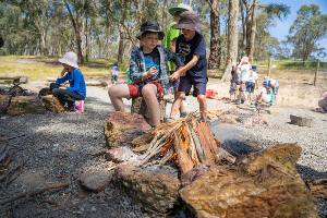 Students adding sticks to burning campfire