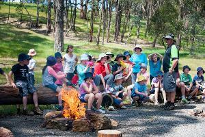 Students sitting around fire listening to activity instructor