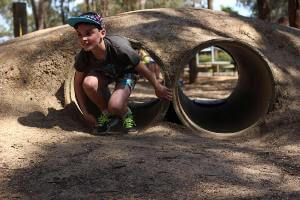 Boy crawling out of tunnel from the commando course