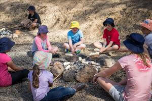 Students cooking damper around campfire