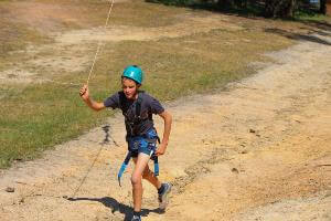 Student in activity harness running flying fox back up the hill.