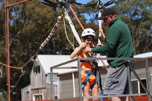 Boy giving thumbs up to camera as he prepares to go on the Giant Swing.