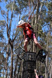 Harnessed student drops two crates off milk crate tower