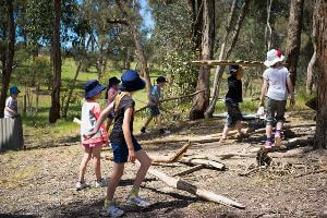 School students carrying logs for hut building