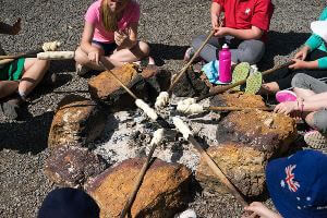 Students cooking damper around campfire