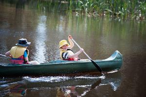 Two students padding in green canoe