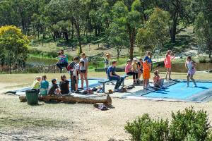 Kids jumping on trampolines with others watch